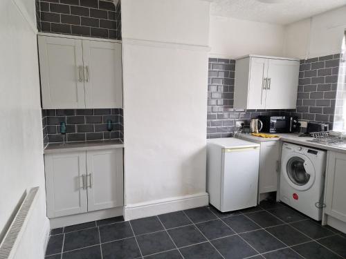 a kitchen with white cabinets and a washer and dryer at Therence Accommodations can sleep up to 4 Guests in Chesterton, Stoke on Trent in Longport