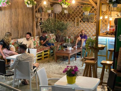 Vlora Backpackers Hostel & Bar LUNGOMARE في فلوره: مجموعة من الناس يجلسون على الطاولات في الغرفة