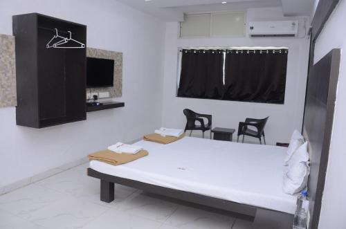 Cette chambre comprend une table, des chaises et un miroir. dans l'établissement Hotel Mangalam, à Kurandvād