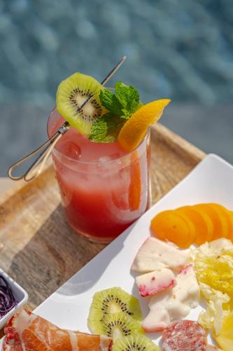 a plate of food with a drink with kiwi and fruit at Kirani Resort in Pantelleria