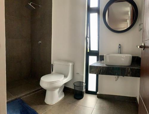 uma casa de banho com um WC, um lavatório e um espelho. em Moderno & Comodo Loft Quetzal em Mérida