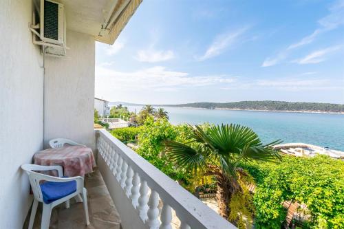 a balcony with a chair and a view of the water at Apartments Biserka in Barbat na Rabu