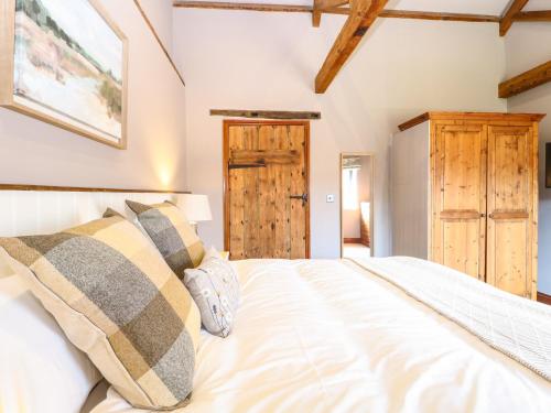 a bedroom with a white bed and a wooden door at Shorthorn Barn in Norwich