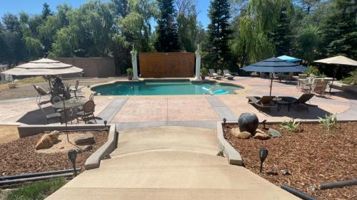 a swimming pool in a yard with chairs and umbrellas at The Oasis in Redding