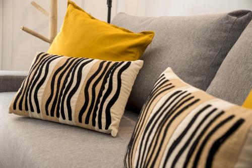 um sofá cinzento com duas almofadas e uma almofada amarela em Modern and cozy- 1 Bedroom 1 Bathroom -Lavapiés em Madri