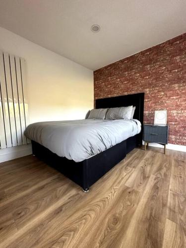 een slaapkamer met een groot bed en een bakstenen muur bij Perfect stay with Dallas Studio in Hayes