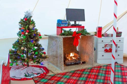 a living room with a christmas tree and a fireplace at Candy Cane Glamp Yurt in the Woods in Columbia