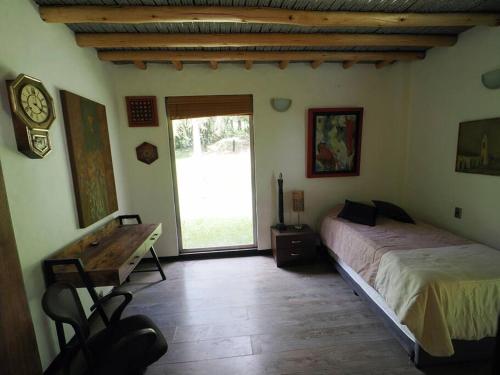 a bedroom with a bed and a desk and a window at La Colina in Tabio