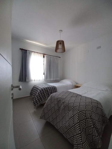 Un dormitorio con dos camas y una ventana. en TERRA CIMINTO, en Villa Rumipal