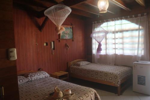 1 dormitorio con 2 camas y ventana en Madera Labrada Lodge Ecologico, en Tarapoto