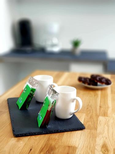 une table avec deux tasses et une assiette de nourriture dans l'établissement Le Chat d'Or - 35m2 - Terrasse - BBQ - WIFI HD, à Amiens