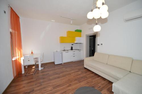 a living room with a white couch and a kitchen at Apartments Windrose in Kotor