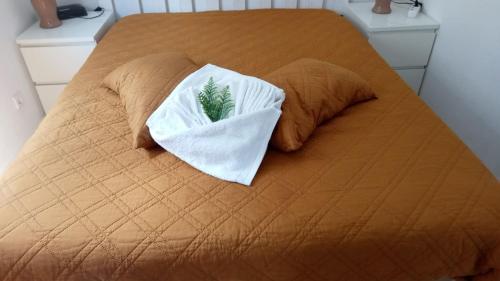 a bed with two pillows with a towel on it at Residencial T2 no Parque Verde in Quinta do Conde