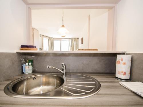 - un évier en argent dans la cuisine avec un miroir dans l'établissement Joli appartement à Chamonix avec balcon, WiFi et animaux acceptés - FR-1-343-157, à Chamonix-Mont-Blanc
