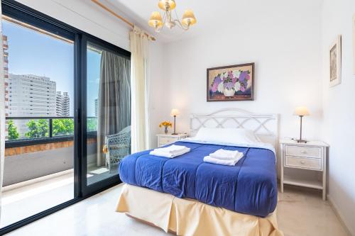 een slaapkamer met een blauw bed en een groot raam bij Gemelos 23 Apartment 5-A Levante Beach in Benidorm