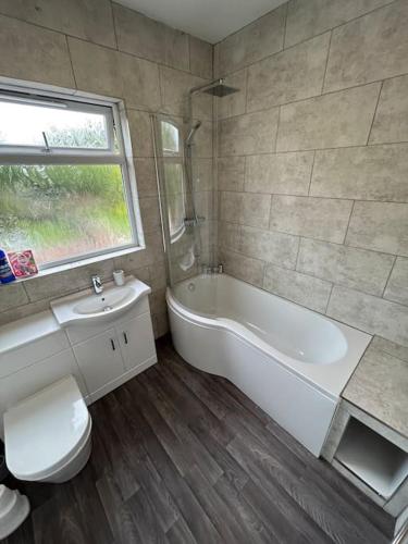 uma casa de banho com uma banheira, um WC e um lavatório. em Bright & Central Home em Church Coppenhall