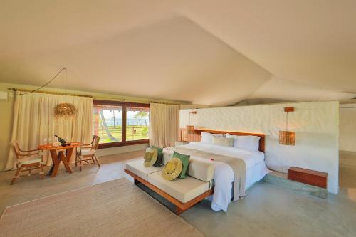 a bedroom with a large bed and a table and chairs at Reserva Jacumã Boutique - Trancoso in Trancoso