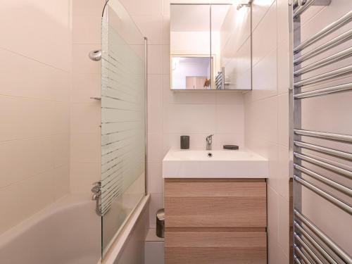 une salle de bain avec un lavabo, un miroir et une baignoire dans l'établissement Charmant appartement au pied des pistes avec wifi - FR-1-694-157, à Val dʼIsère