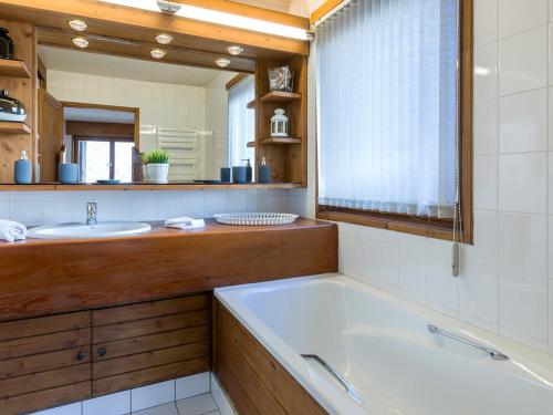 une salle de bain avec une baignoire, un lavabo et un miroir dans l'établissement Chalet semi-indépendant avec terrasse et WiFi à Val-d'Isère - FR-1-694-267, à Val dʼIsère