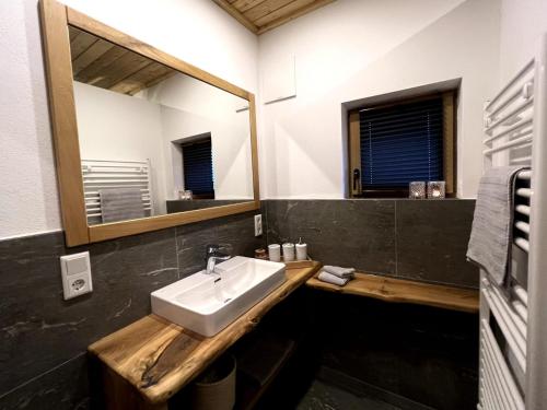 La salle de bains est pourvue d'un lavabo et d'un miroir. dans l'établissement Riedlfeld Chalet, à Dienten am Hochkönig