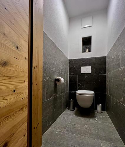 a bathroom with a toilet and a wooden door at Riedlfeld Chalet in Dienten am Hochkönig