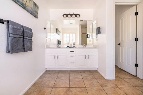 a white bathroom with a sink and a mirror at AZ Sun Palm Retreat w/optional Private Heated Pool in Surprise