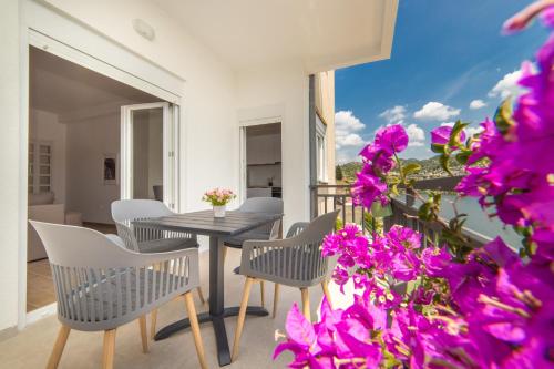 einen Balkon mit einem Tisch, Stühlen und lila Blumen in der Unterkunft Lakeview Apartments in Ploče
