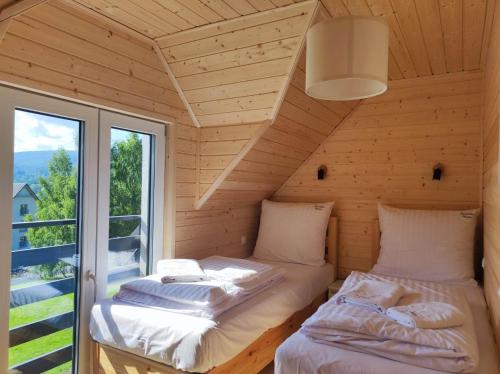 two beds in a room with a window at Tyrolska Chata in Świeradów-Zdrój