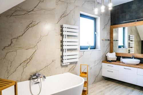 uma casa de banho com uma banheira branca e uma parede em mármore em Dom nad Zatoką em Osłonino