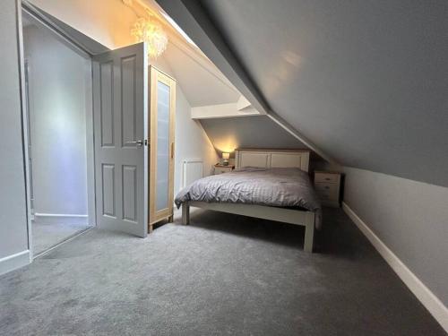 een zolderkamer met een bed en een open deur bij Fresh & Spacious House in Rhyl