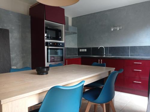 une cuisine avec une table en bois et des chaises bleues dans l'établissement Maison de charme avec patio et terrasse de toit, à Estagel