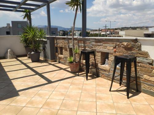 two black stools on a patio with a stone fireplace at #Roof(pool)garden Private in Pikérmion