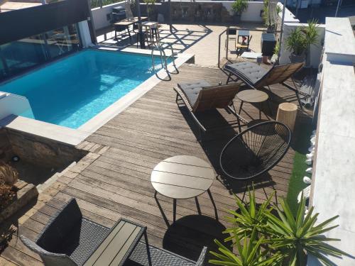 a deck with chairs and a swimming pool with a table at #Roof(pool)garden Private in Pikérmion