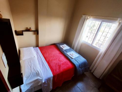 a small bedroom with a bed and a window at Hotel AEROPUERTO Jujuy in Perico