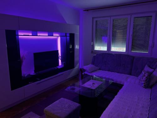 a purple living room with a couch and a tv at Apartman Čapljina in Čapljina