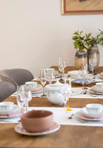a wooden table with glasses and dishes on it at Can Candiu Establecimiento de 2 casas enteras in Vall-Llobrega
