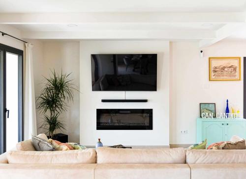 uma sala de estar com um sofá e uma televisão na parede em Can Candiu Establecimiento de 2 casas enteras em Vall-Llobrega