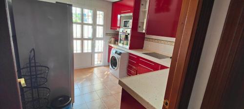 a kitchen with red cabinets and a washing machine at CASA EN CAMPO DE GOLF CERCA DE LA PLAYA in Jerez de la Frontera
