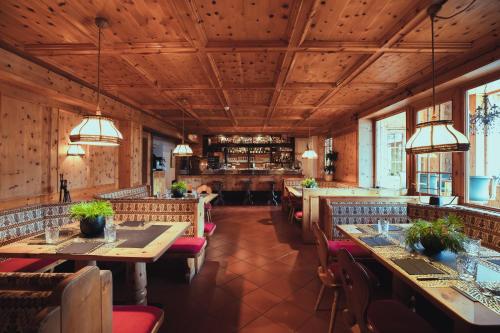 un restaurante con techos de madera, mesas y sillas en PLOSE Parkhotel & Residence en Bressanone