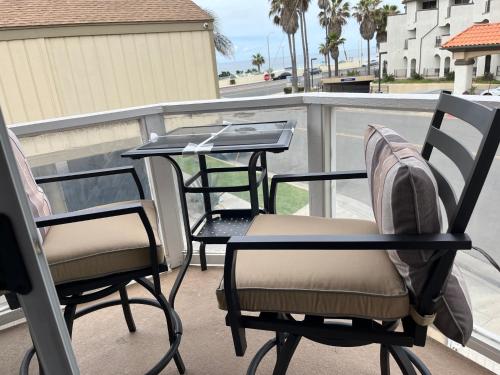 two chairs and a table on a balcony with a table at Pacific Breeze Right Next to Huntington Beach Pier! Steps from Beach!! in Huntington Beach