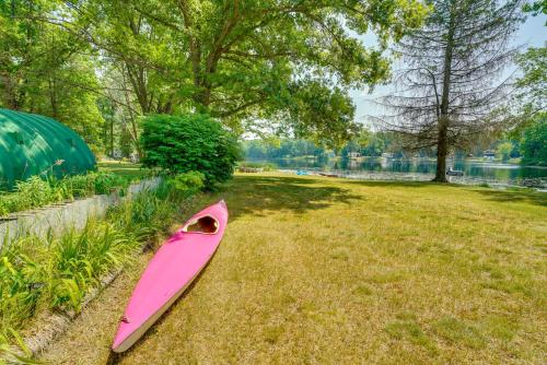 a pink kayak sitting on the grass near a lake at Lakefront Brohman Retreat with Dock and Fire Pit! in Brohman