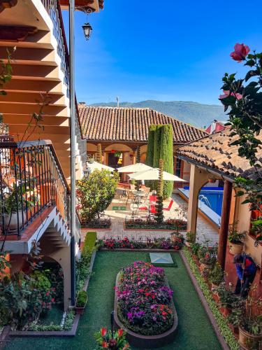 an outdoor patio with a garden with flowers and tables at Hotel La Casa de Mamá in San Cristóbal de Las Casas