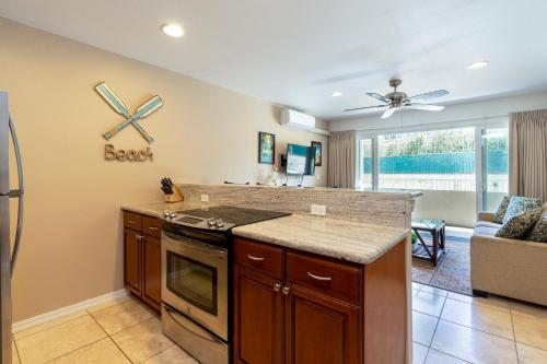a kitchen with a stove top oven next to a living room at 2 Bedroom Kapaa Condo, Pool, AC, Beach Access KK116 in Kapaa