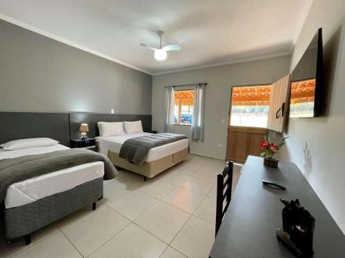 Habitación de hotel con 2 camas y mesa en Santana's Ranch en São Pedro