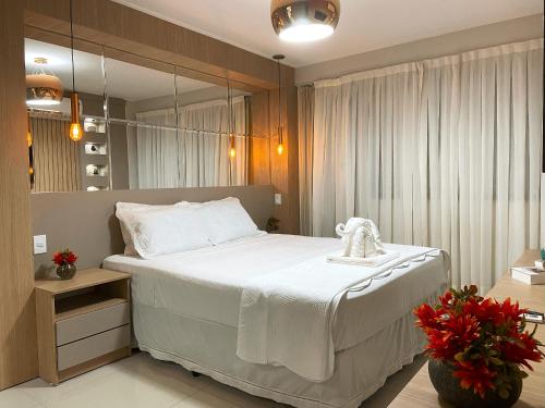 um quarto com uma grande cama branca e um espelho em Charmoso apto em Barra Bali - Destino BSM 108 na Barra de São Miguel