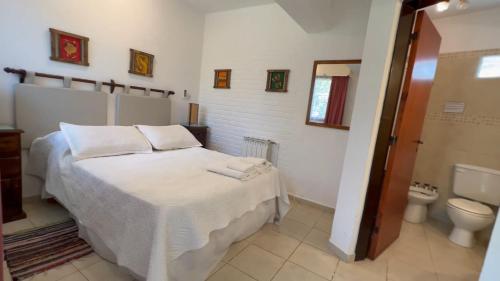 1 dormitorio con cama blanca y aseo en La Casa de Pipa, en Mina Clavero