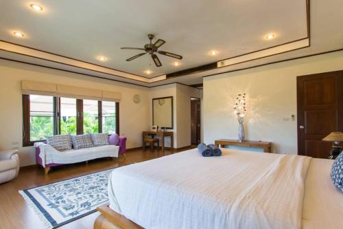 プーケットタウンにあるSpacious villa with private garden by CapitalProの大きな白いベッドとソファのある寝室