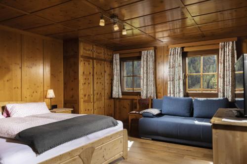 um quarto com uma cama azul e um sofá em Haus Arnika em Sankt Jakob in Defereggen