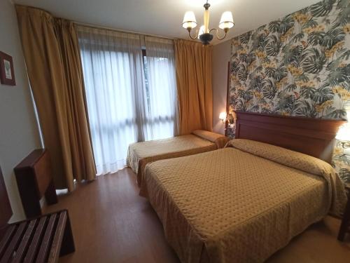 a hotel room with two beds and a window at La Estrada in Arriondas