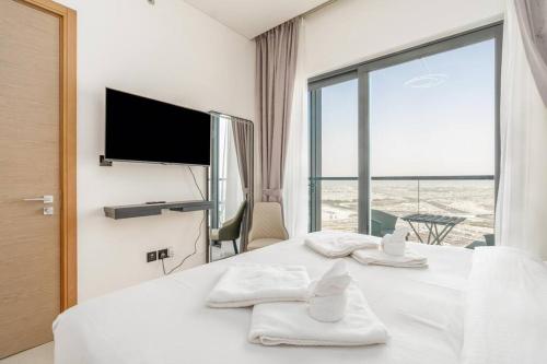 een slaapkamer met een wit bed en een groot raam bij Modern 1bdr - 10min from Burj Khalifa - Sobha Waves in Dubai